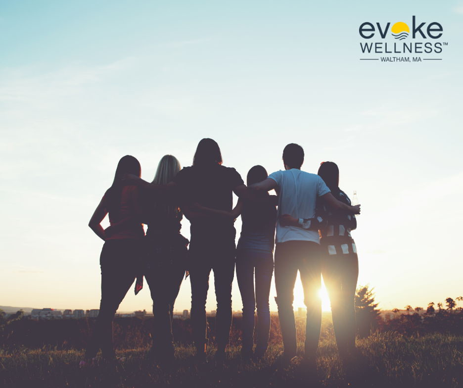 Group of people in prescription drug treatment climb hill and watch sunset